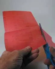 When hand sanding, maximize the life of your 8 x 10- inch sheet of sandpaper by folding as follows. First, fold it into quarters and crease to create straight lines for cutting. Unfold and cut a slit along one of the creases. The slit should end at the center of the sheet.