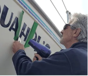 The heat from a hairdryer melts the adhesive under the vinyl and allows you to free the letter from the hull with the scraper. (Photo/ Marc Robic)