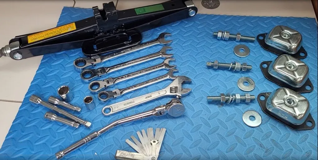 These are all of the tools and parts you'll need to replace your engine mounts: proper size wrenches, a ratchet, sockets and extensions, sparkplug feeler gauge set, new engine mounts and hardware, and a car jack. (Photo/ Marc Robic)